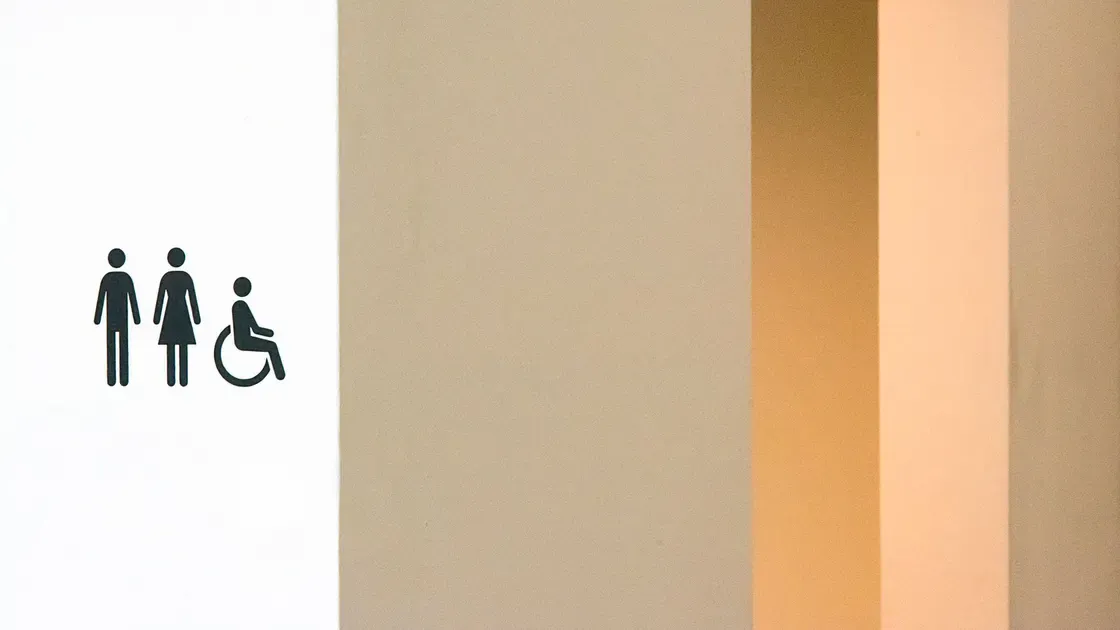 Skylt med symboler för dam, herr och rullstol vid en tillgänglig toalett
