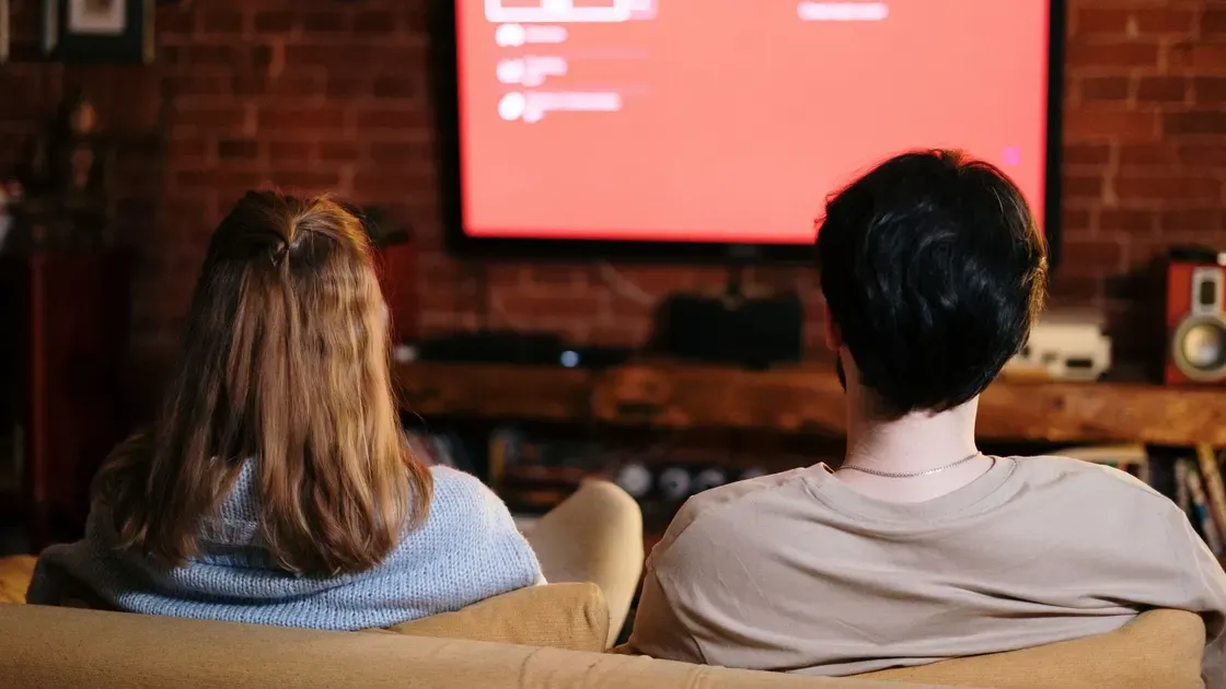 Två personer som tittar på tv med högtalare på tv-bänken