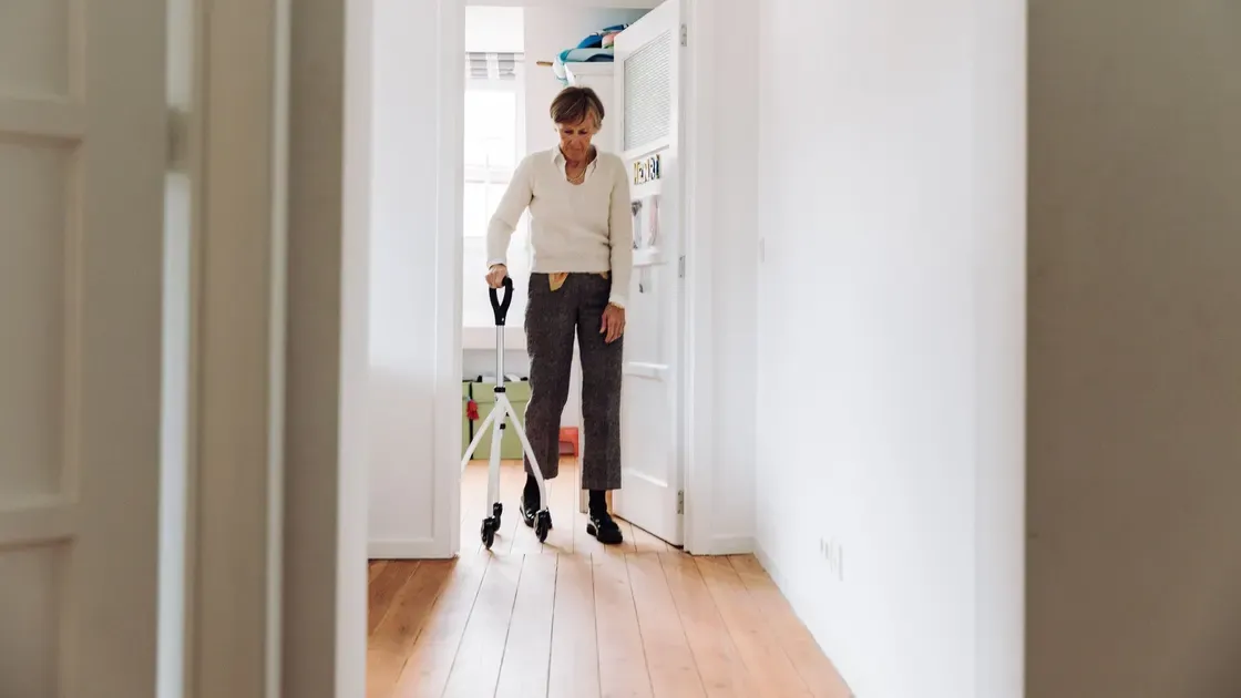 Äldre man som går med gåstöd i en ljus hall
