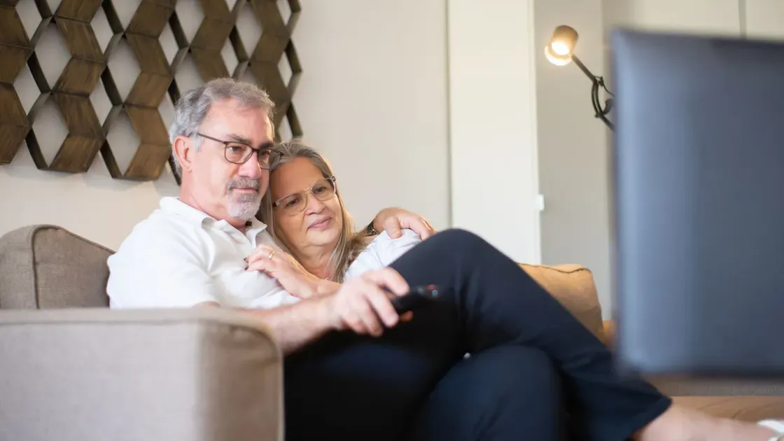 Par i soffan som ser på tv med fjärrkontrollen i handen