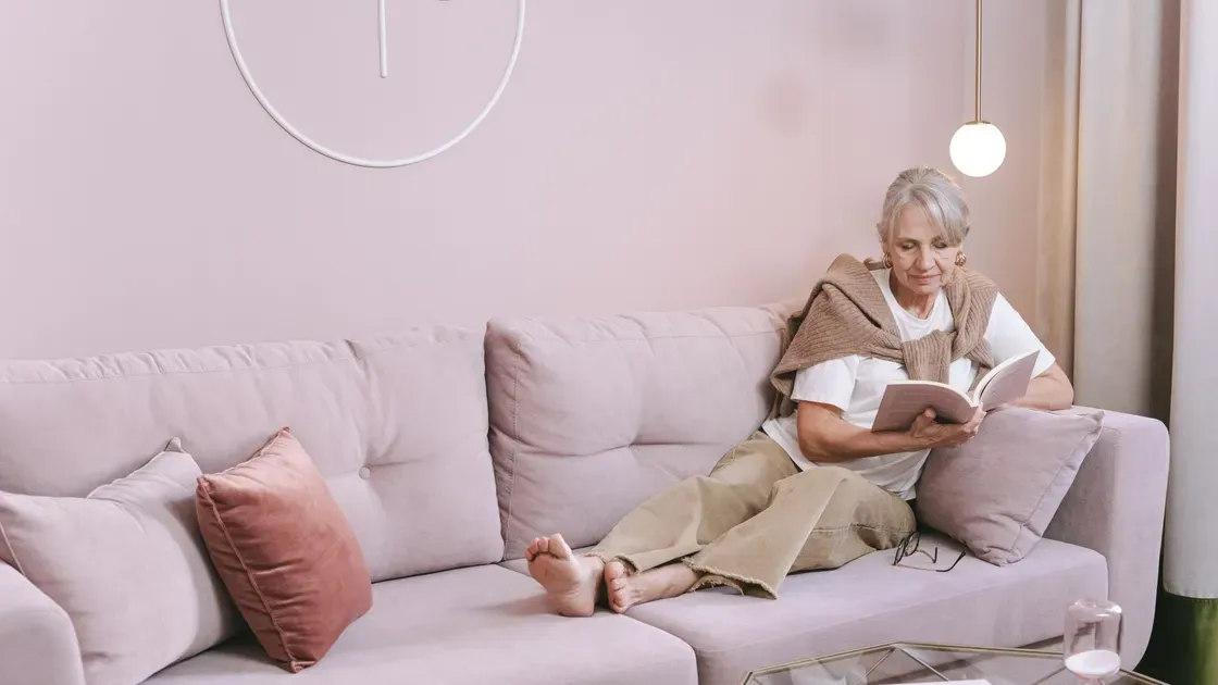 Äldre kvinna som läser i en ljus soffa
